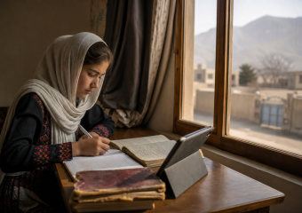 A girl in a headscarf writes beside an open book and tablet, seated by a window overlooking a mountainous town