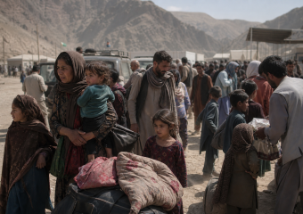 A crowd of families with luggage gathers in a mountainous border crossing