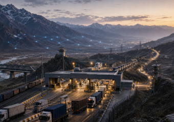 Mountain border checkpoint with trucks, freight trains, power lines, and a glowing digital network across the valley