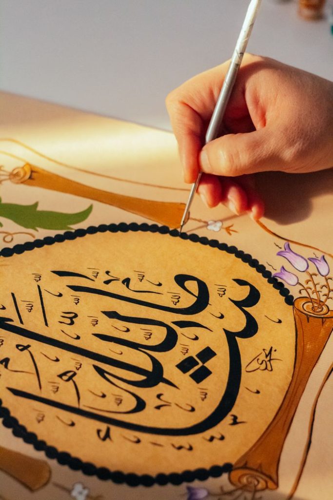 Close-up of hand painting Arabic calligraphy with intricate details.