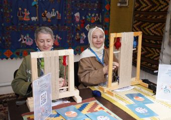 Two women engaging in traditional textile weaving at an arts and crafts workshop, demonstrating cultural heritage.