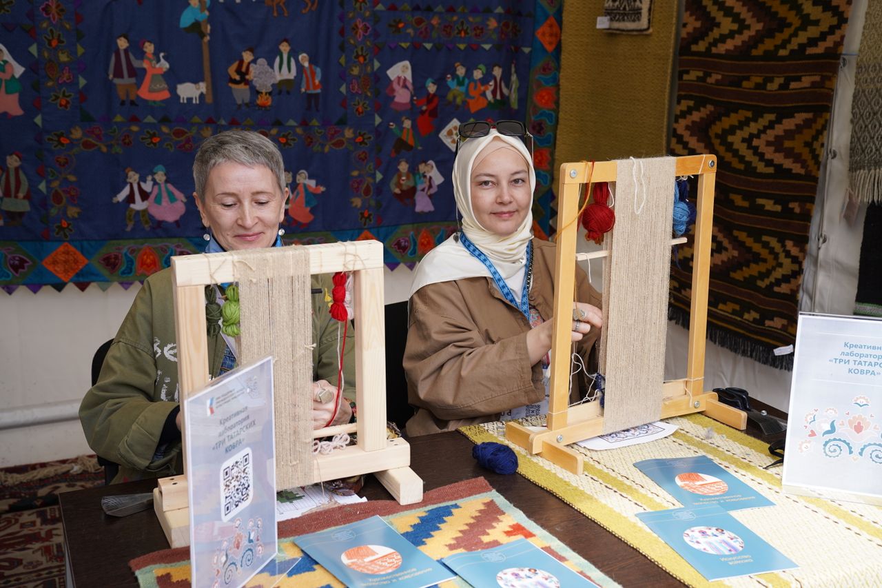 Two women engaging in traditional textile weaving at an arts and crafts workshop, demonstrating cultural heritage.