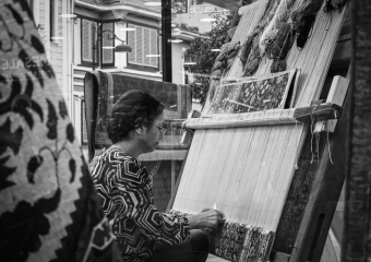 Black and white photo of a weaver crafting a traditional carpet in Istanbul, Turkey.