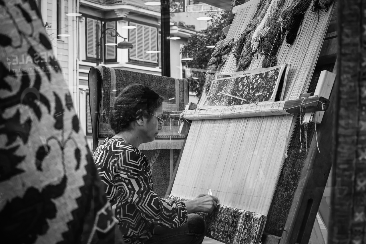 Black and white photo of a weaver crafting a traditional carpet in Istanbul, Turkey.